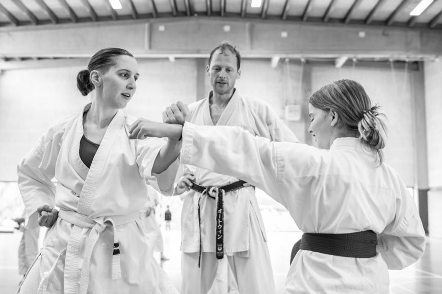 Ortwin, hoofdtrainer van karateclub Anzegem geeft les aan 2 karateka's die een kumite oefening doen